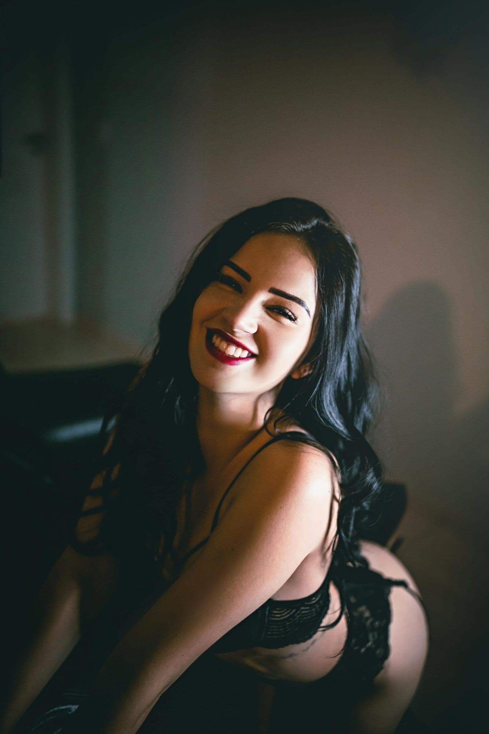 Brunette escort in zwarte lingerie en rode lipstick